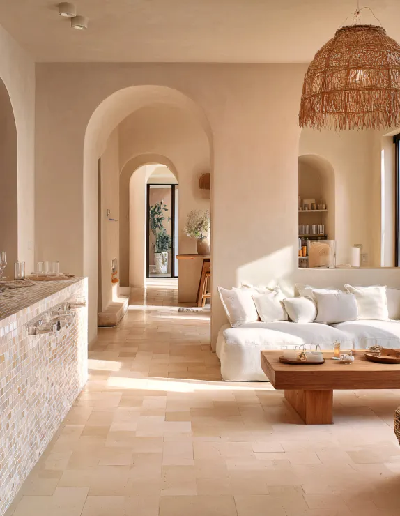 Photo intérieure d'un logement aux couleurs douces et aux arches arrondies, canapé blanc, éclairage ensoleillé